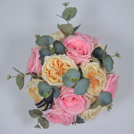Bouquet of pink and yellow roses with greenery on a light gray background