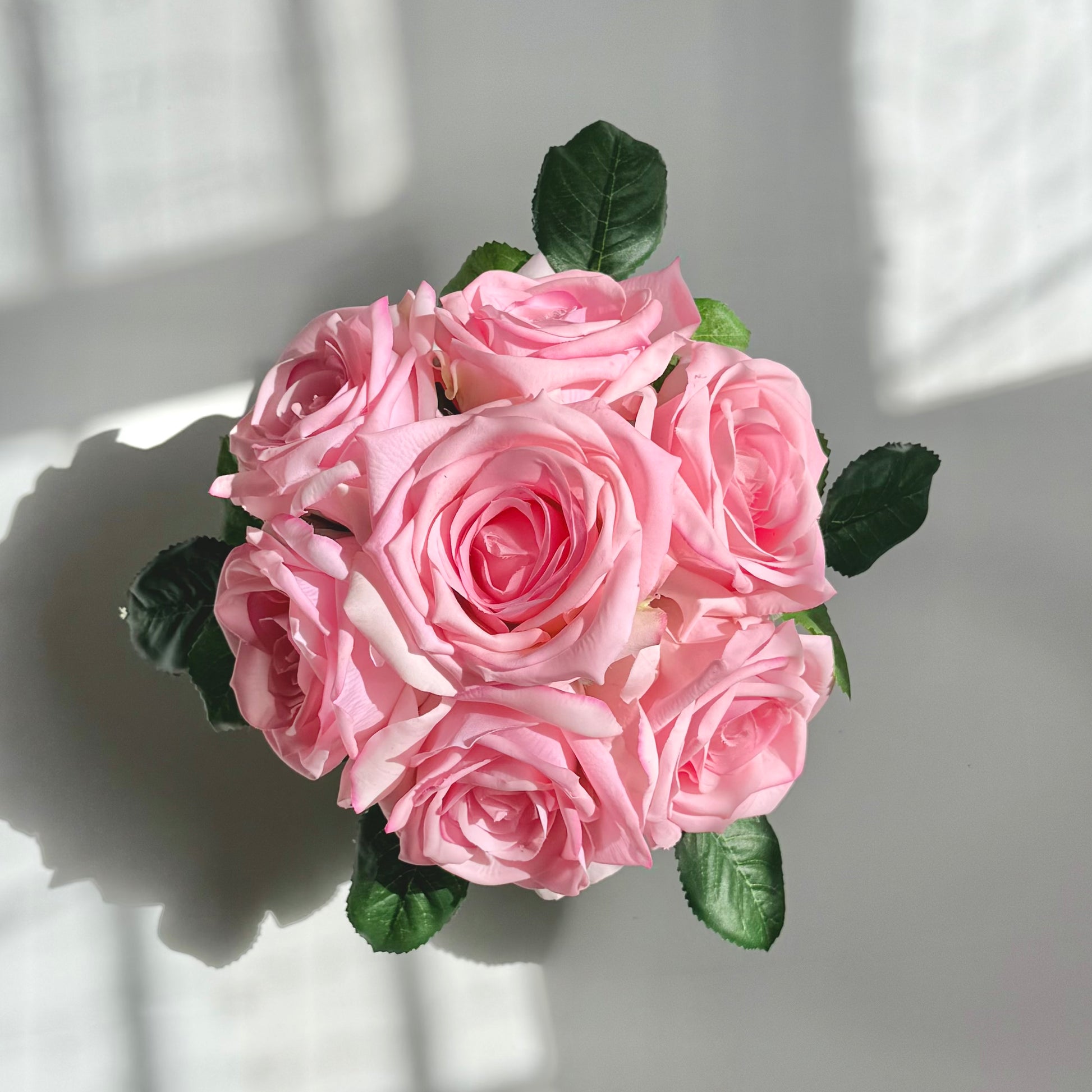 Bouquet of pink roses with green leaves on a light background