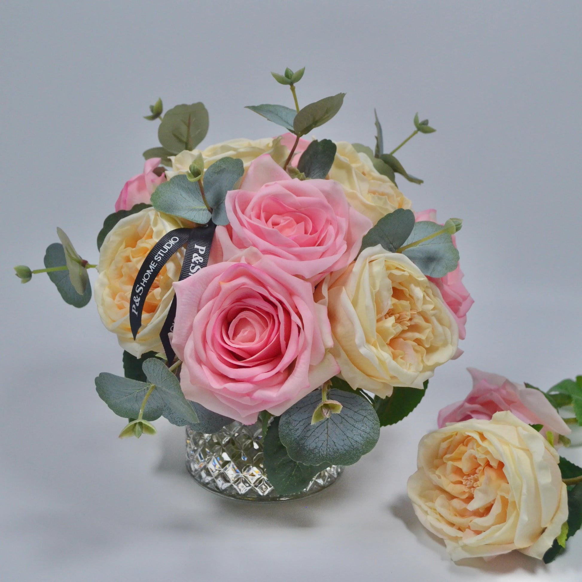 Bouquet of pink and yellow roses with green leaves on a gray background