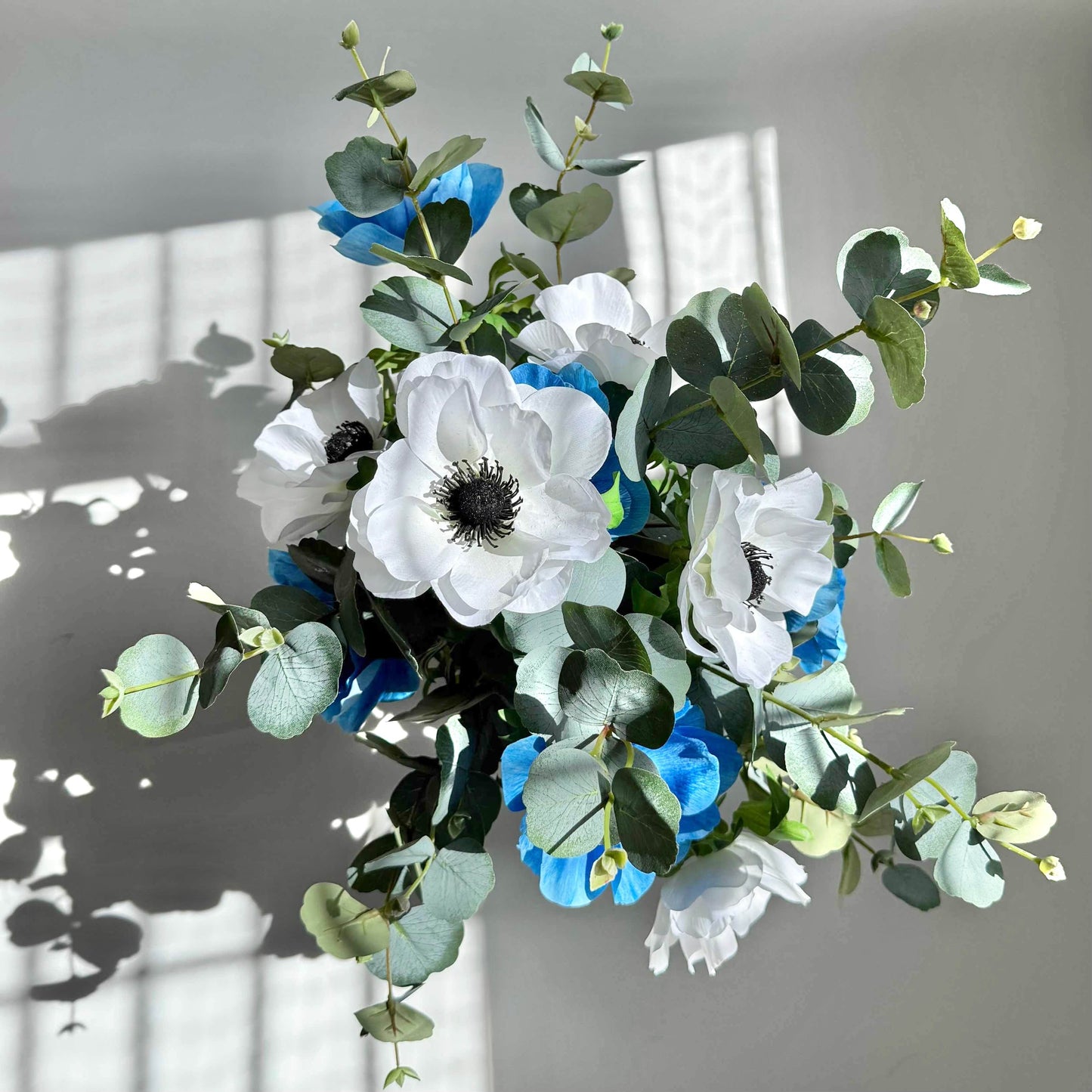 Bouquet of white and blue flowers with green leaves on a gray background