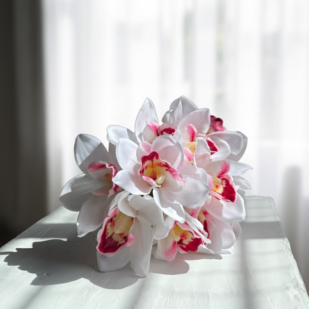 Bouquet of white and pink orchids on a white surface with a blurred background