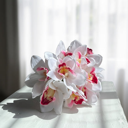 Bouquet of white and pink orchids on a white surface with a blurred background