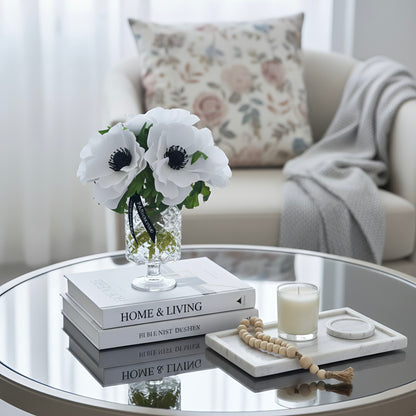 Decorative setup on a glass coffee table with books, flowers, and a candle.