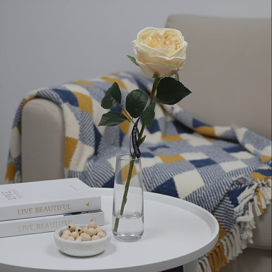 White table with a vase of flowers, books, and a bowl in a cozy living room setting.