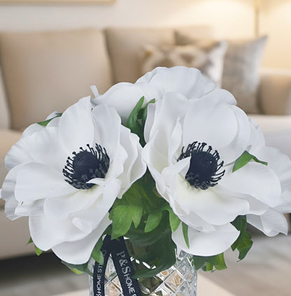 Bouquet of white flowers with black centers in a clear vase on a blurred background