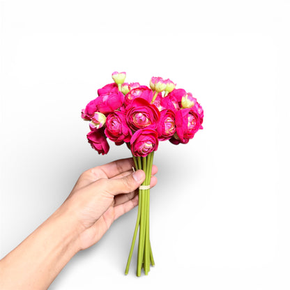 Hand holding a bouquet of bright pink flowers against a white background