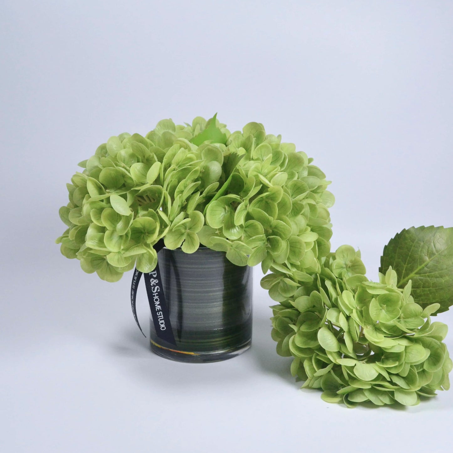 Green floral arrangement with a visible brand label on a light gray background